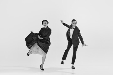 Black and white. Happy, positive, smiling young people, man and woman in elegant clothes dancing lindy hop. Concept of hobby, retro dance, vintage style, choreography, beauty. Monochrome art. Ad
