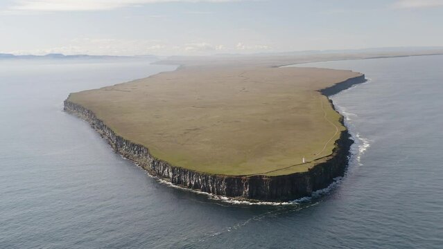 Aerial view of beautiful Langanes peninsula with green landscape and steep cliffs surrounded by ocean in Iceland