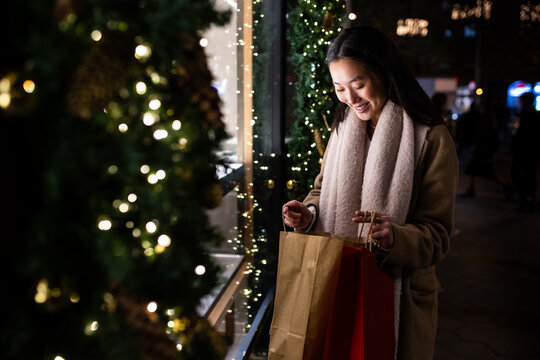 Happy young lady looking inside shopping bags in the street. satisfied female holding shopping bags in Christmas.