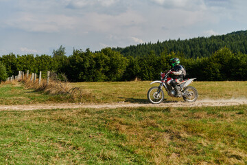 A professional motocross rider exhilaratingly riding a treacherous off-road forest trail on their...