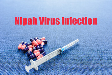 Nipah virus concept.A blue background with the inscription NIPAH VIRUS INFECTION.Top view, syringe...