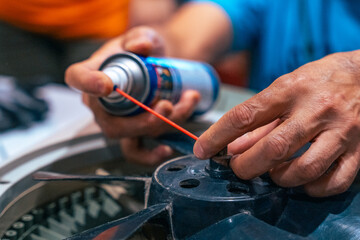 Electrician spraying a can of oil to fan close up