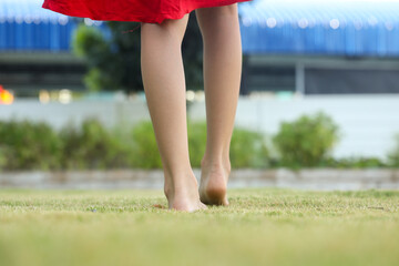 Children's feet are walking barefoot on the green grass. Self-massage on natural surfaces to...