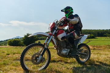 Fototapeta na wymiar A motorcyclist equipped with professional gear, rides motocross on perilous meadows, training for an upcoming competition.