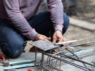 Labor constructor ties steel wire to secure bars rod for reinforcement of concrete at flooring structure at construction site. House building project with cement strong floor engineering
