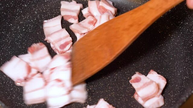 roasting of salted pork fatback on a red-hot pan, close-up