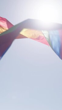 Vertical video slow motion of the rainbow flag waving during a pride parade in a city streets