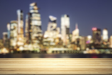 Empty wooden table top with beautiful blurry skyscrapers at evening on background, mock up