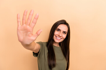 Photo of friendly excited girl dressed khaki t-shirt waving you arm hello isolated beige color background © deagreez