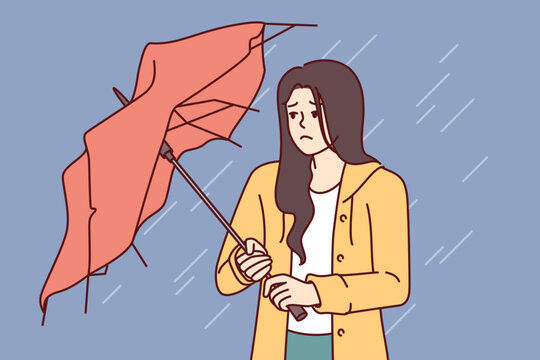 Wet Woman Stands With Broken Umbrella In Heavy Rain, And Is Sad Because Of Cold And Strong Wind. Upset Girl Walking Down Street During Storm And Autumn Rain Needs Waterproof Clothes