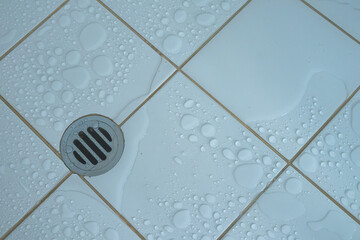 Top view of drainage hole stainless and shower water stain with  wet floor on white tile ...