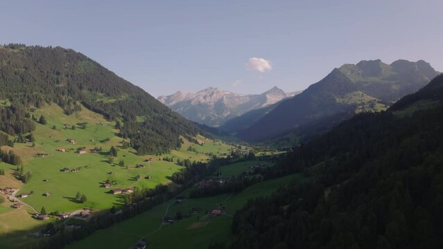 Beautiful mountain scenery with green valley and alpine peaks in background. Flight above picturesque landscape scenery. Gstaad, Switzerland