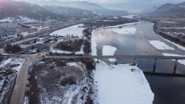 Aerial view of the Lafarge bridge over the South Thompson frozen river in cold winter in Kamloops