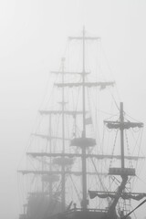 Sailboat sailing on a serene ocean partially obscured by a mysterious fog