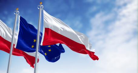 Flags of Poland and the European Union waving in the wind on a clear day - obrazy, fototapety, plakaty