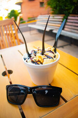 Cup of the French vanilla ice cream with plastic spoons and eyeglasses on a wooden table