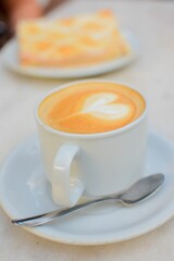 Vertical closeup shot of a cup of latte coffee with a heart design on the top of the liquid
