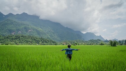 Fototapeta na wymiar Beautiful view of a female enjoying the view in the rice field in Lao