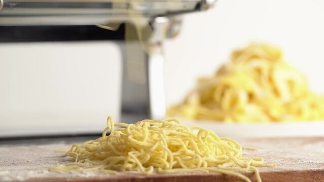 Kids hand sprinkles flour on fresh home made pasta. Cooking, chef baker puts pasta in a pile. Making pasta process, close up.