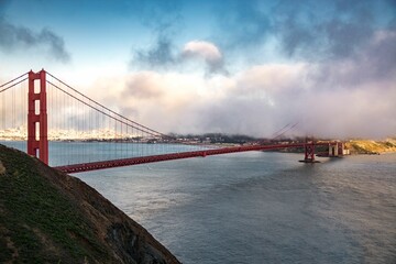 a view of a golden gate bridge surrounded by clouds, in the foreground