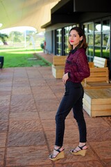 White young woman wearing a casual outfit posing for the camera at the cafe, vertical