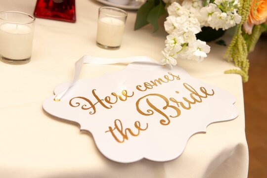 Elegant wedding table setting with a wooden sign featuring 'here comes the bride'