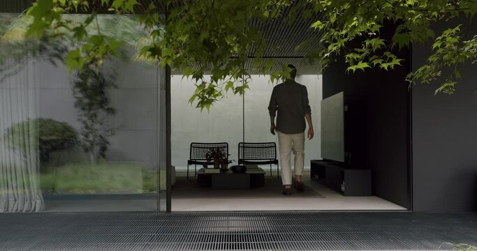 Back view on young man enter living room at modern cottage house with glass open sliding door