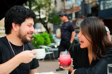 Closeup shot of a male and female couple laughing and holding refreshing drinks