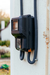 Black electric meter on the wall of the house. 