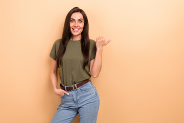 Photo of ecstatic funny woman with straight hairdo dressed khaki t-shirt directing empty space discount isolated on beige color background