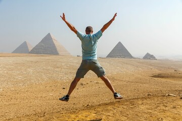 Rear view of a man jumping against the famous pyramids of Giza in Egypt