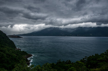 Aerial seascape between mountains under a dramatic cloudy gray sky