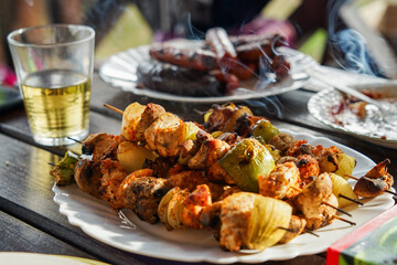 Assorted delicious grilled meat with vegetables on white plate on the picnic table for family BBQ...