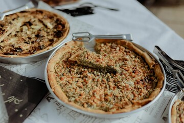 Selection of freshly-baked pies arranged on white paper with knives, ready to be enjoyed