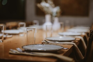 Elegant table setting with white plates and glasses on a wood table of the restaurant