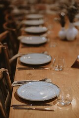 Elegant table setting with white plates and glasses on a wooden table in the restaurant