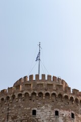 view from below of the top of a stone castle with a wind indicator