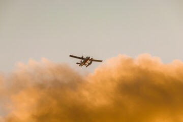 Fototapeta na wymiar Low-angle shot of an airplane below the clouds and skies