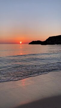 Vertical landscape scene of Cala salada beach with orange sunset horizon sly in Ibiza, Spain