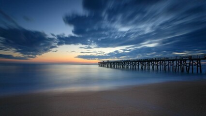 Beautiful sunrise over the Atlantic Ocean with a wooden pier in the background