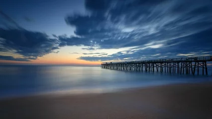 Fotobehang Beautiful sunrise over the Atlantic Ocean with a wooden pier in the background © Rusty Nails/Wirestock Creators
