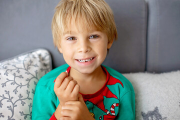 Sweet blond preschool child, boy, loosing his first milk tooth, smiling happily, holding the little tooth