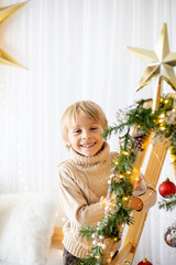 Beautiful blond child, young school boy, playing in a decorated home with knitted toys