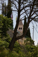 Vertical of an old church tower seen behind green trees on a sunny day in Split, Croatia