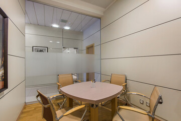 A small meeting room in the office with a glass wall and furniture in pastel colors.