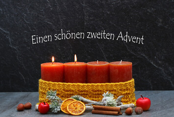 Zweiter Advent: Zwei brennenden Kerze mit Weihnachtsdekoration vor dunkelm Hintergrund. Mit dem...
