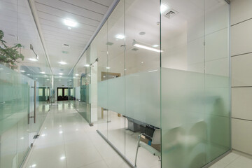 Modern office space divided by glass partitions into work areas.