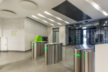 The entrance to the lobby of the office building is decorated with light tiles and with a turnstile access system.