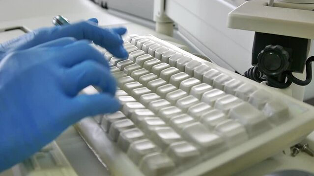 doctor in medical gloves typing on the keyboard of an office computer