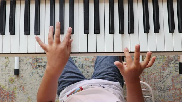 Cute child, boy, playing piano at home, learning how to play music instrument